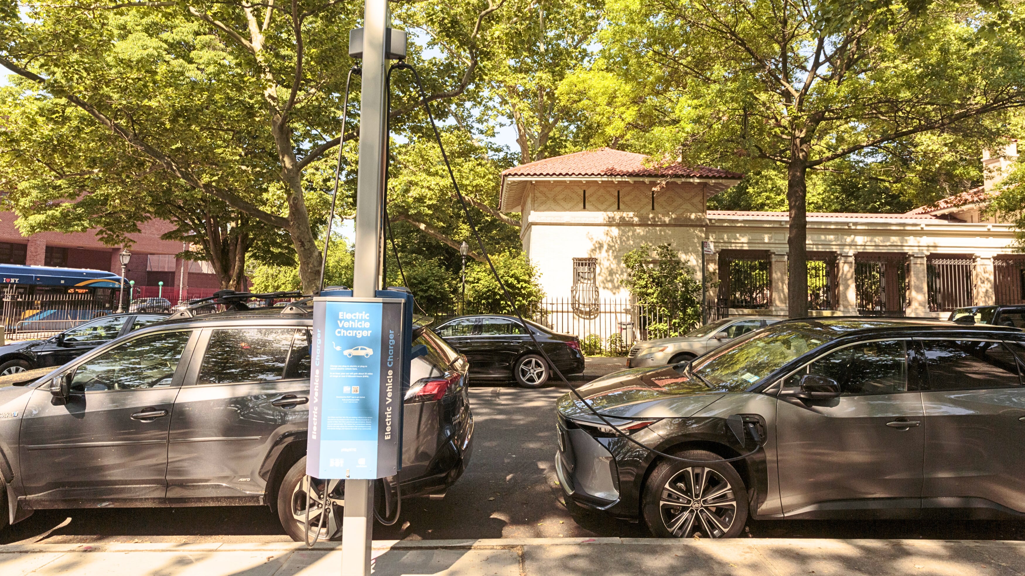 Vehicles are shown parked on a street and plugged into an EV charger.