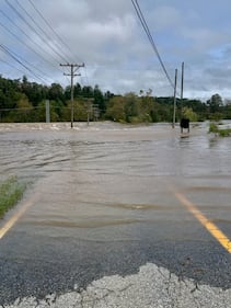 Flood water rushes over a highway.